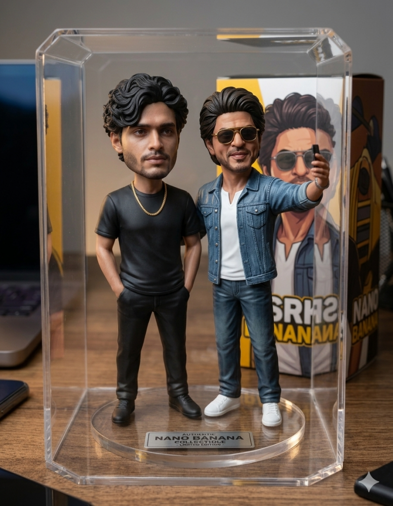 Desk setup featuring Nano Banana collectible figurines inside clear hexagonal glass display case on circular base engraved 'Nano Banana Edition': left figure bearded man with curly hair in black t-shirt and pants striking casual pose; right figure Shah Rukh Khan in denim jacket jeans sneakers sunglasses snapping selfie gesture; matching yellow SRK Nano Banana box packaging behind case; wooden desk with laptop keyboard in soft ambient lighting casting realistic shadows, hyper-detailed matte plastic sculpt with accurate facial features clothing textures viral 2026 Gemini AI style.