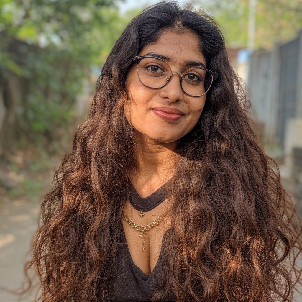 AI-upscaled portrait of a young South Asian woman with long wavy hair and glasses outdoors, generated with FLUX 2 Pro for Dzinepixel’s AI image-upscaling comparison with Nano Banana 2 Lite, Grok Imagine, and ChatGPT 1.5